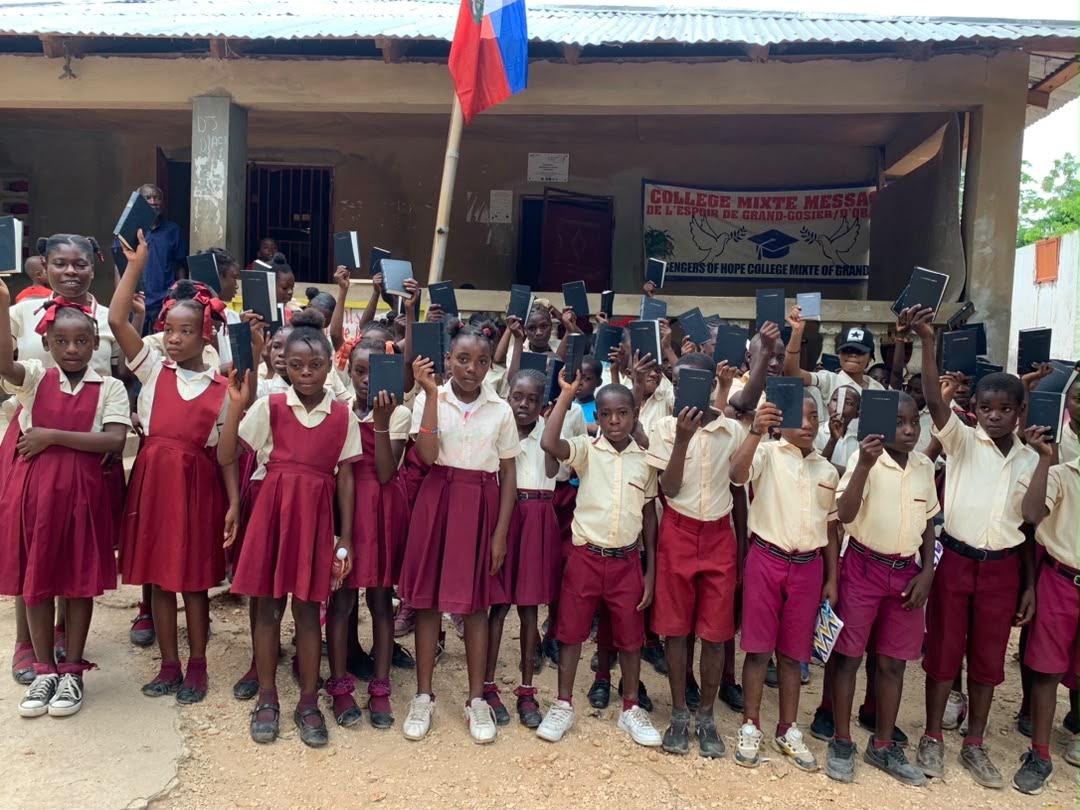 Students and adults gathered outside a school, holding books