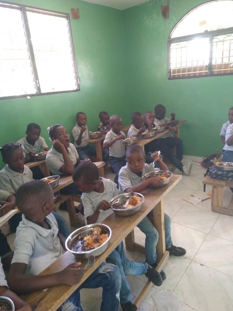Schoolchildren eating from bowls at classroom desks